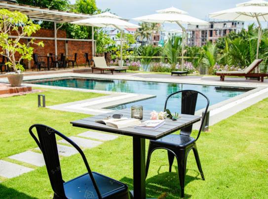 una mesa y sillas junto a una piscina en Ylang Garden Villa, en Hoi An
