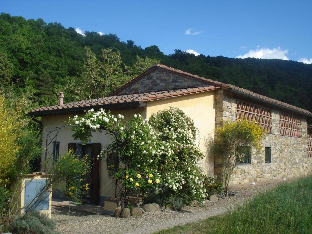 a small stone house with a bush with white flowers at Il Cielo Bio - Il più piccolo B&B del Chianti in Greve in Chianti
