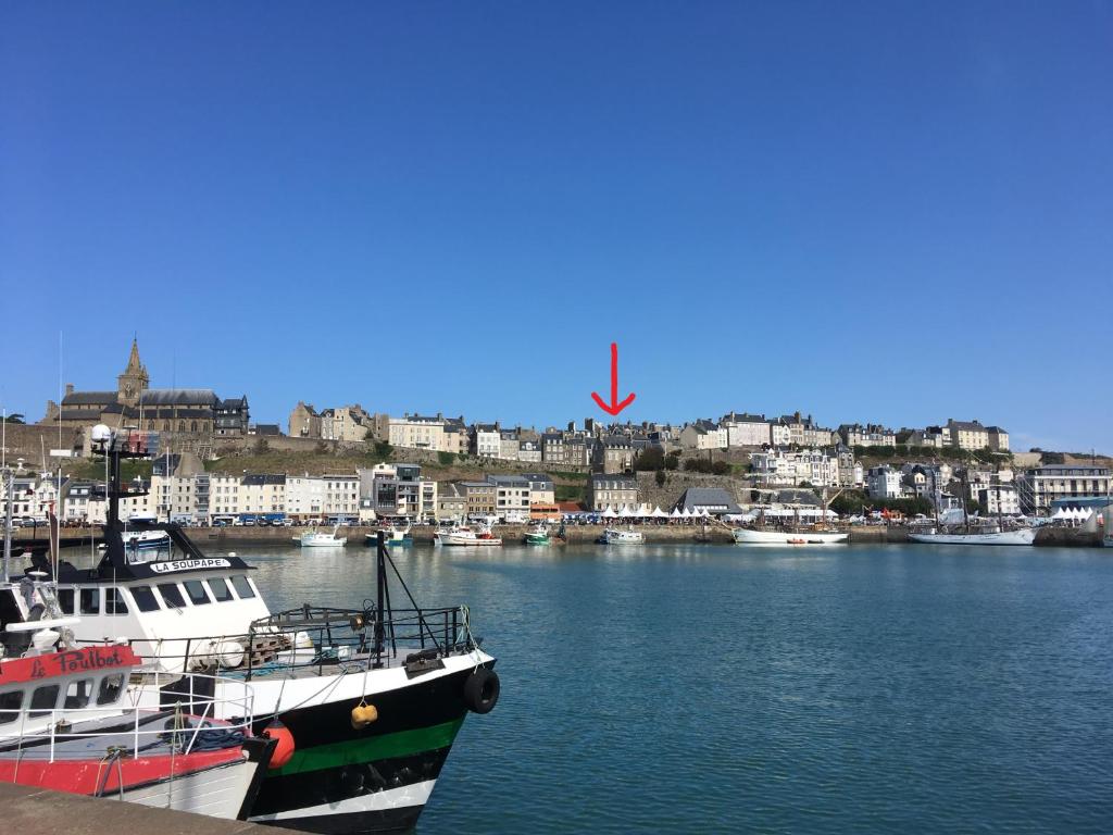 deux bateaux amarrés dans un port avec une ville en arrière-plan dans l'établissement Appartement vue mer Granville, à Granville