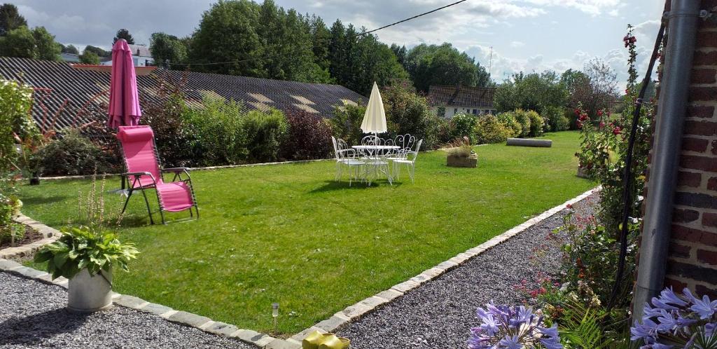 a garden with a table and chairs and an umbrella at Le rucher in Lès-Fontaine