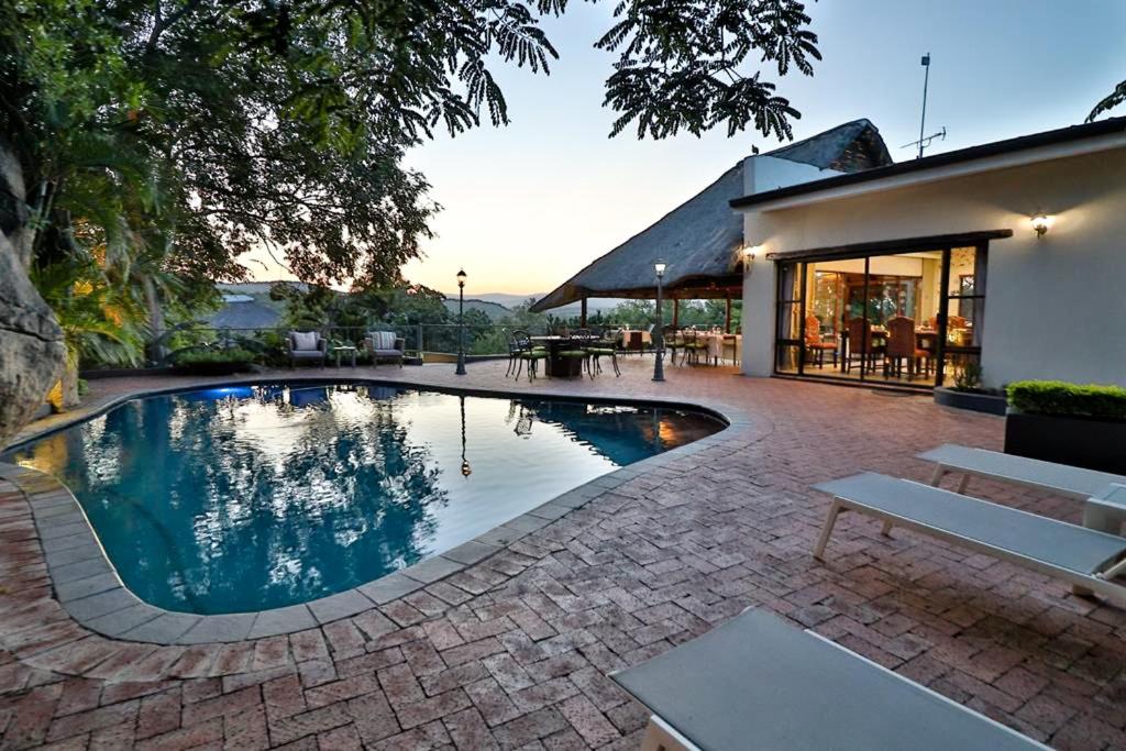 a swimming pool in a yard with a house at La Roca Guest House in Nelspruit