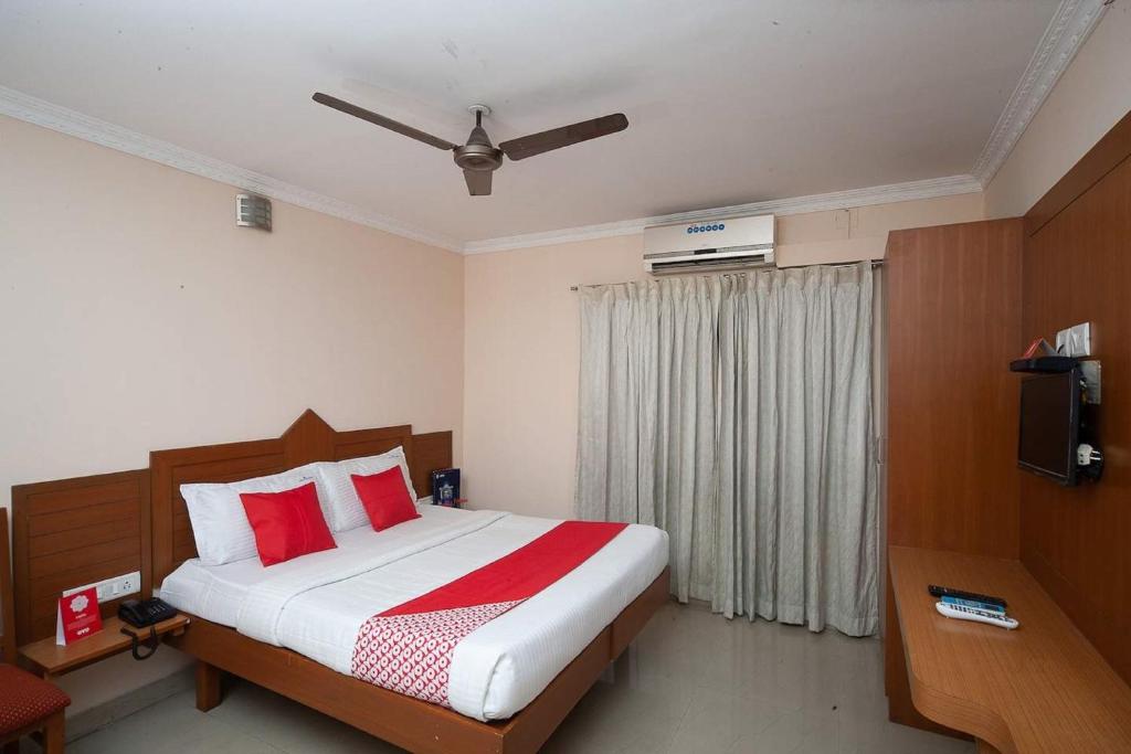 a bedroom with a bed with red pillows and a television at Silver Cloud Hotel Sholinganallur in Chennai