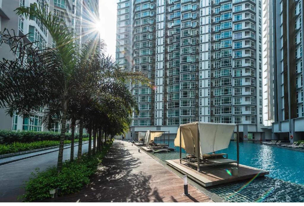 a swimming pool with palm trees and tall buildings at Central Residence Homestay2 @ Sungai Besi, Kuala Lumpur in Kuala Lumpur