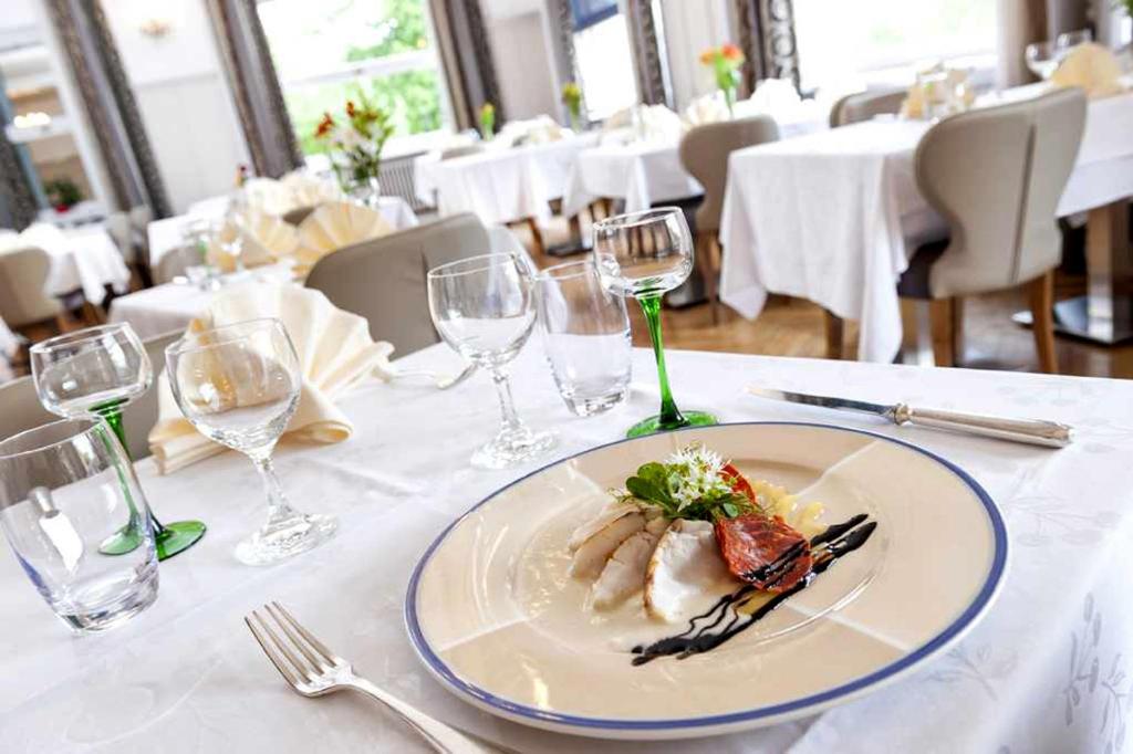 a plate of food on a table with wine glasses at Hotel Restaurant Perle Des Vosges in Muhlbach-sur-Munster