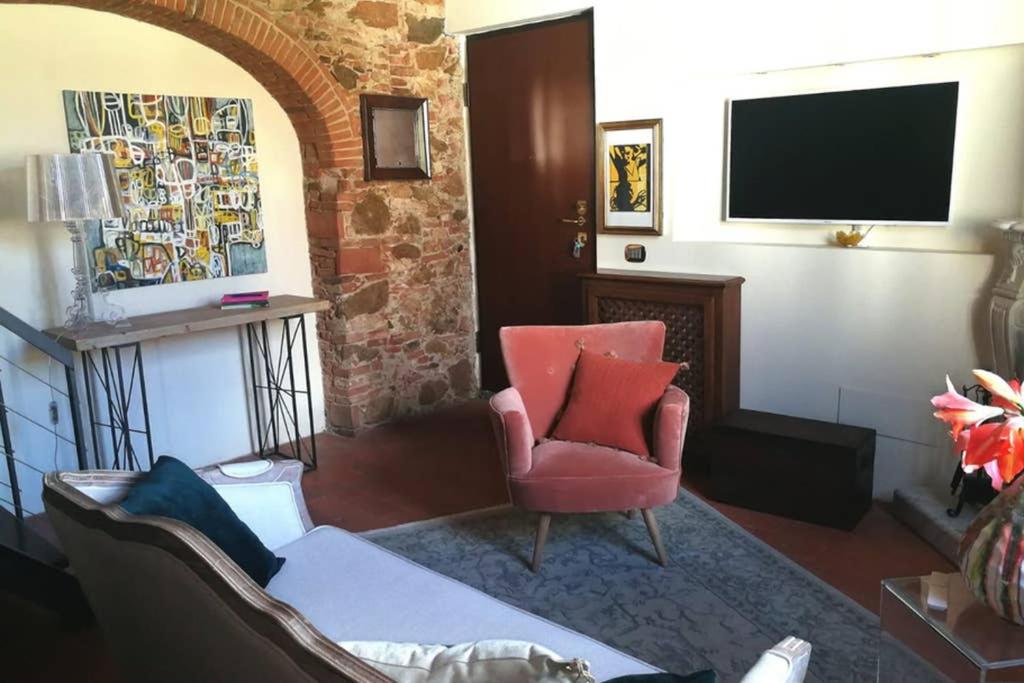 a living room with a red chair and a television at La dimora di Kinzica in Pisa