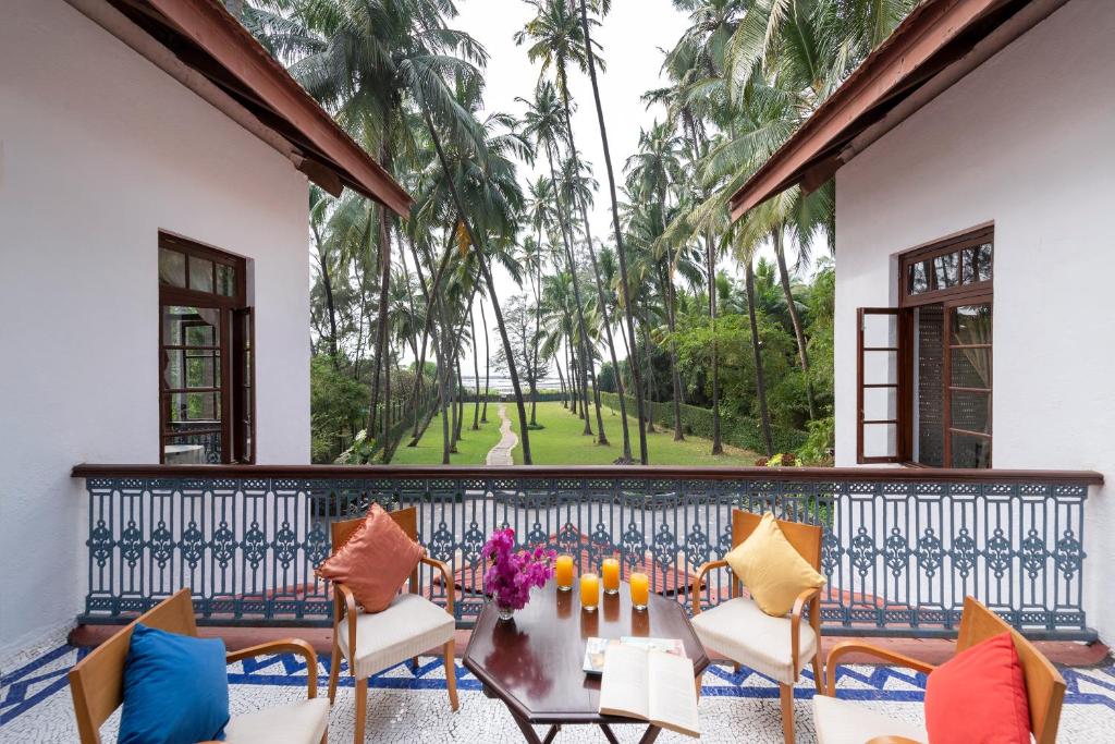 uma varanda com cadeiras e uma mesa com flores em SaffronStays Thalassea, Alibaug - picturesque sea-facing villa with colonial decor em Alibag