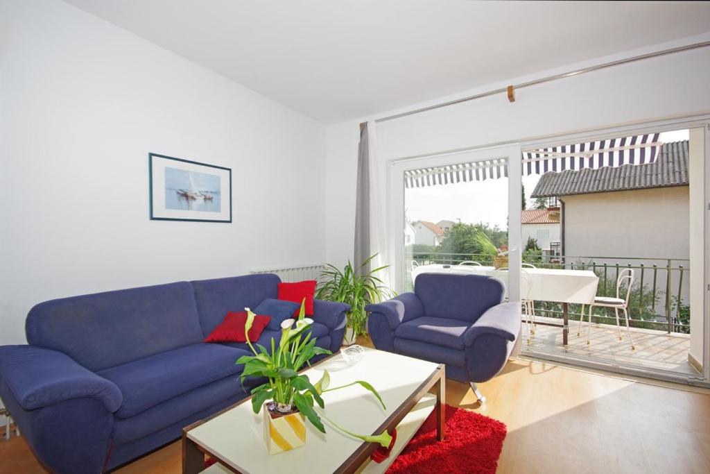 a living room with a blue couch and two chairs at Marija Apartments in Pirovac