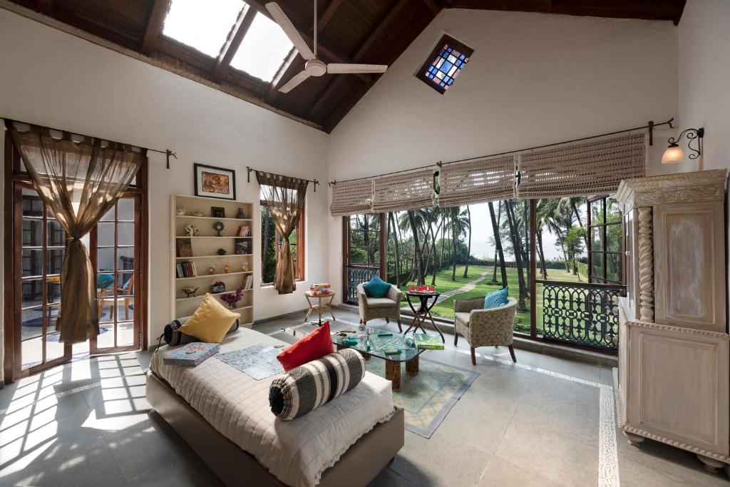 a bedroom with a bed and a living room at SaffronStays Thalassea, Alibaug - picturesque sea-facing villa with colonial decor in Alibaug