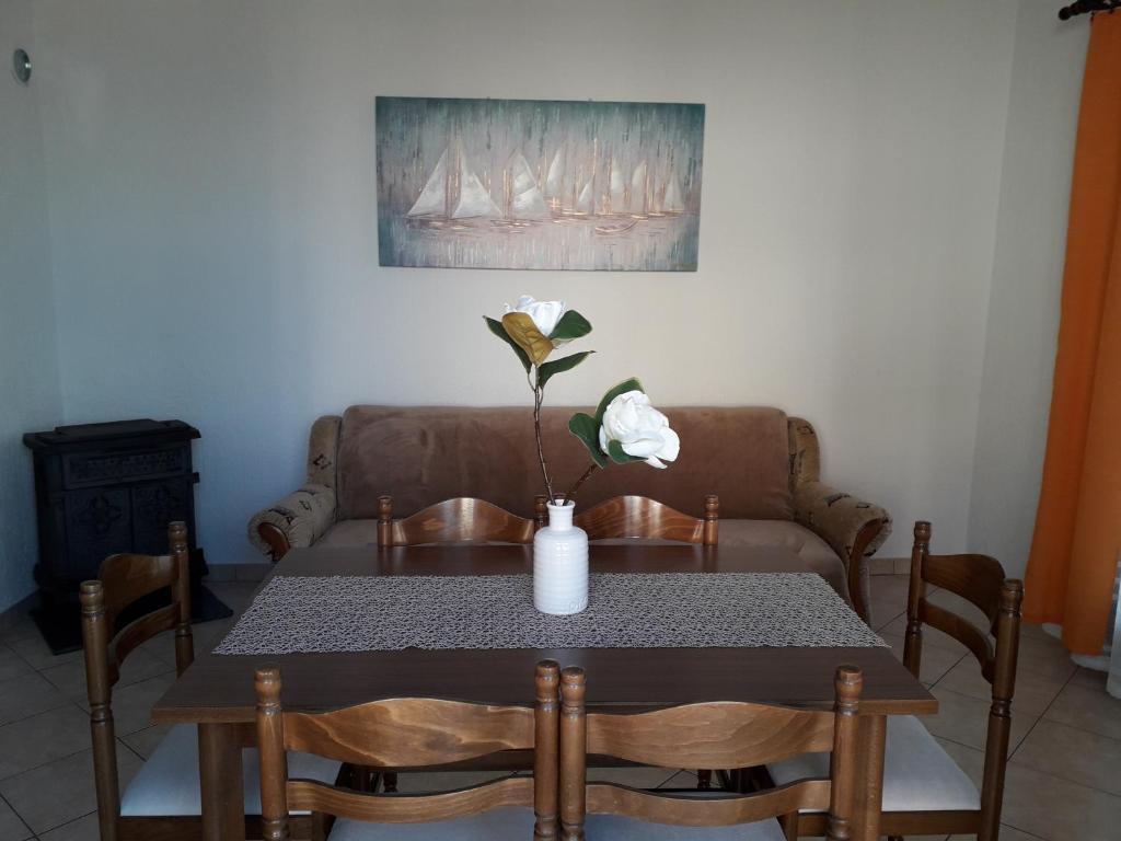 a dining room table with a vase of flowers on it at Delfin Apartments in Sveti Juraj