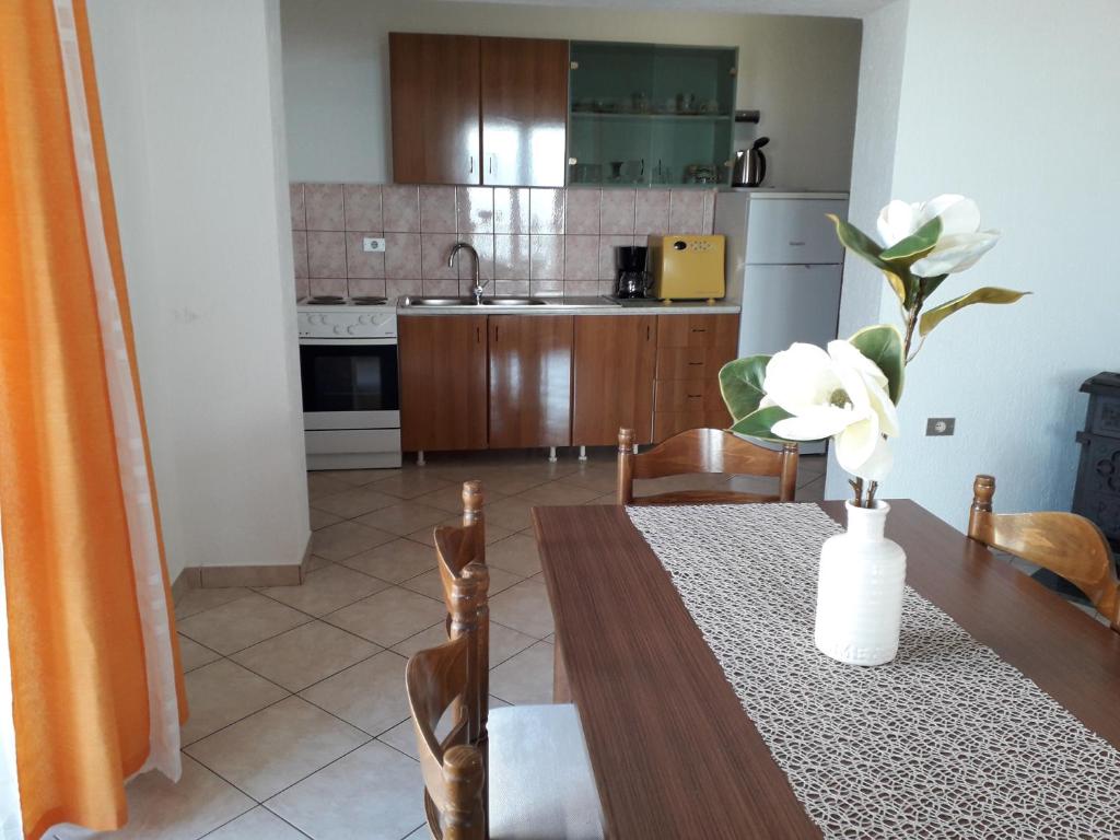 a kitchen with a table with a vase of flowers on it at Delfin Apartments in Sveti Juraj