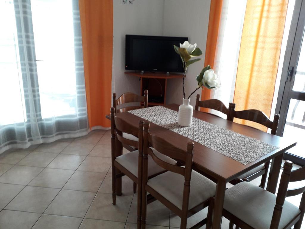 a dining room table with a vase of flowers on it at Delfin Apartments in Sveti Juraj