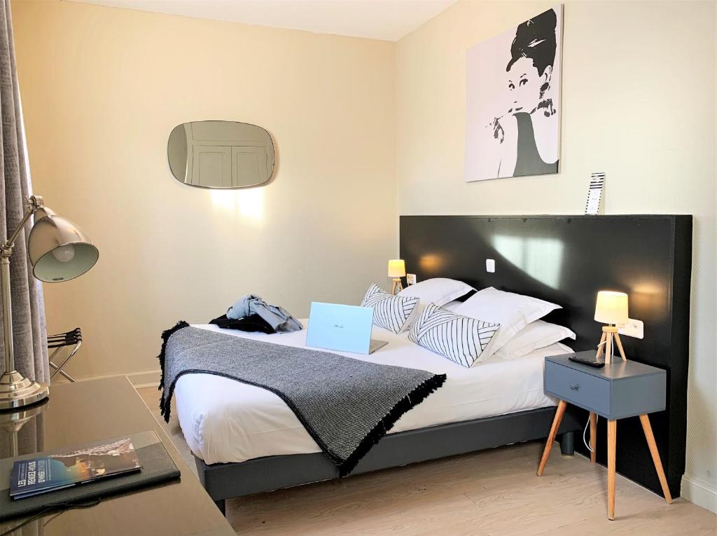 a bedroom with a bed with a laptop on it at Hôtel Jules in Le Touquet-Paris-Plage