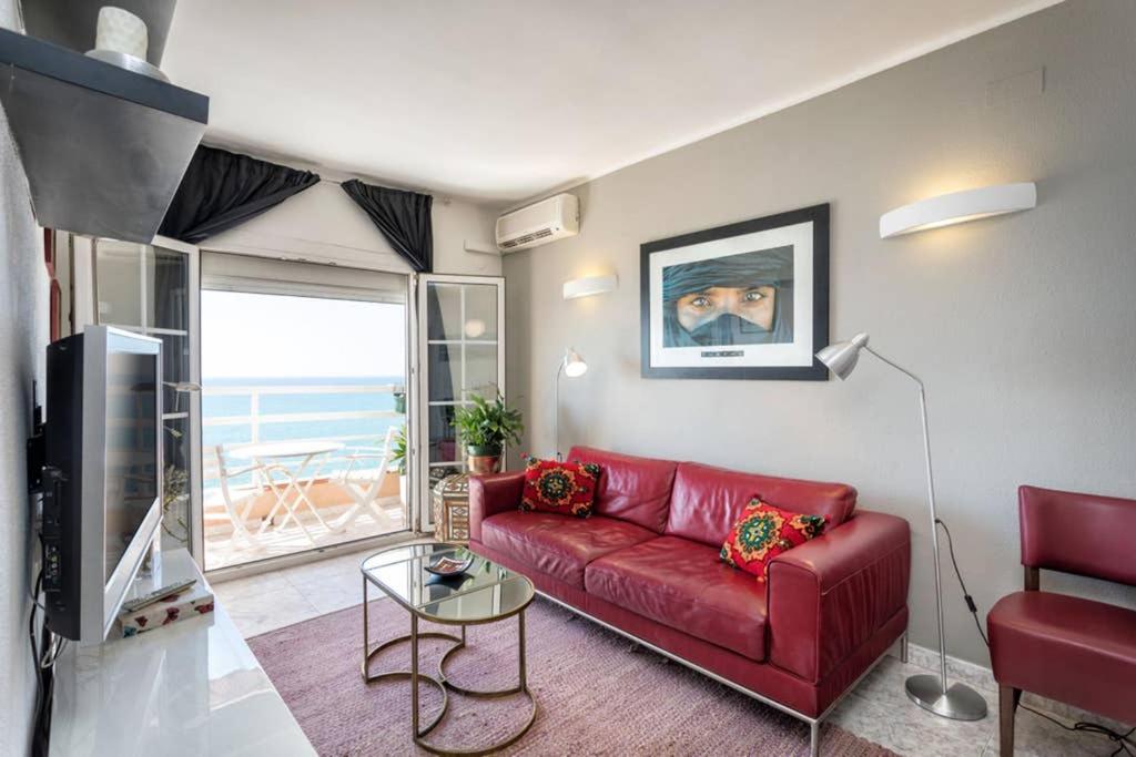 un sofá rojo en la sala de estar con vistas al océano en Apartment in front of the Beach, en Pineda de Mar
