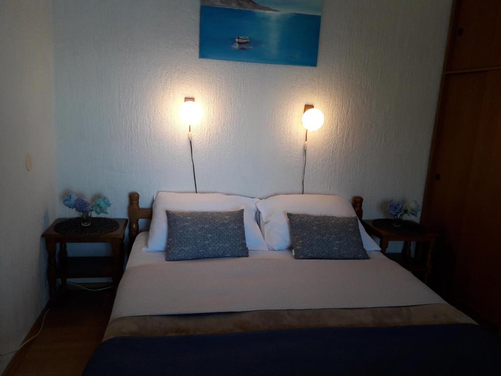a bedroom with a bed with two lights on the wall at Delfin Apartments in Sveti Juraj