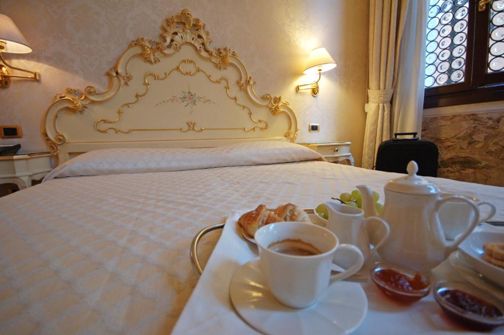 a bed with a tray of food and cups of coffee at Hotel Torino in Venice