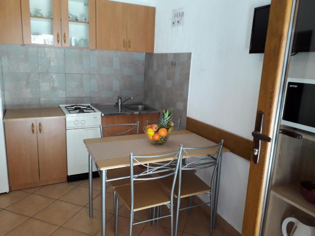 a kitchen with a table with a bowl of fruit on it at Delfin Apartments in Sveti Juraj