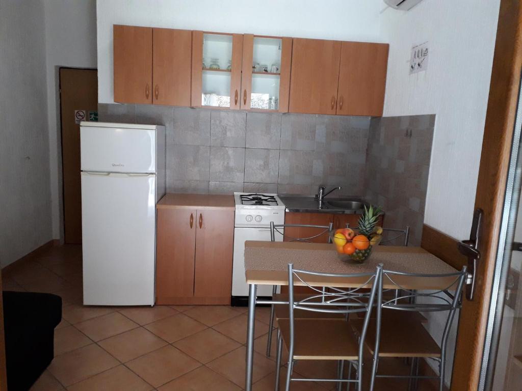 a kitchen with a table and a white refrigerator at Delfin Apartments in Sveti Juraj