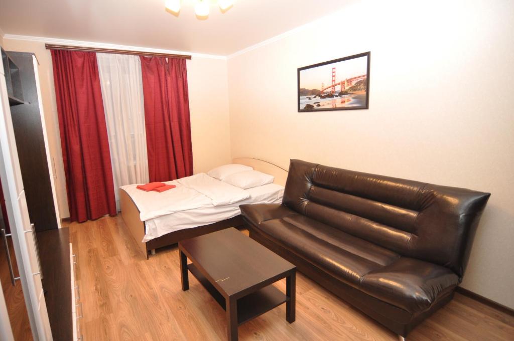 uma sala de estar com um sofá de couro e uma cama em Apartment on Tolstogo em Kursk