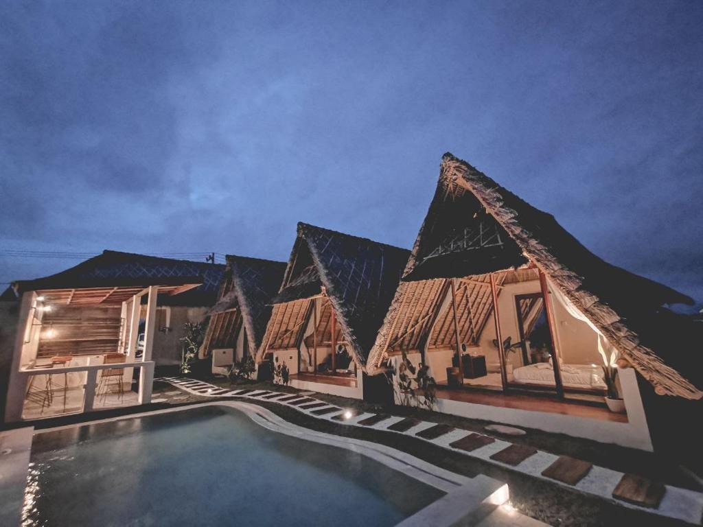 a row of houses with a swimming pool at night at Capila Villa Bali in Canggu