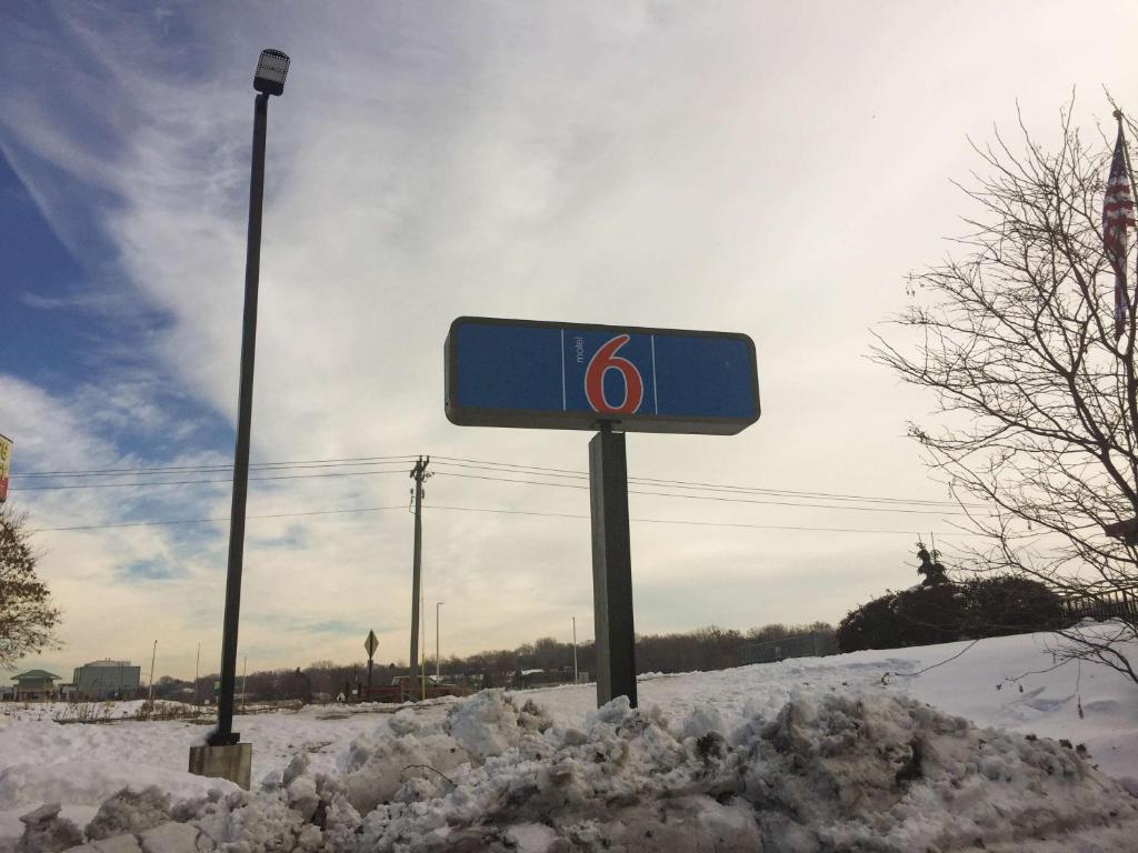 un panneau bleu dans la neige dans une rue dans l'établissement Motel 6-Burnsville, MN, à Burnsville