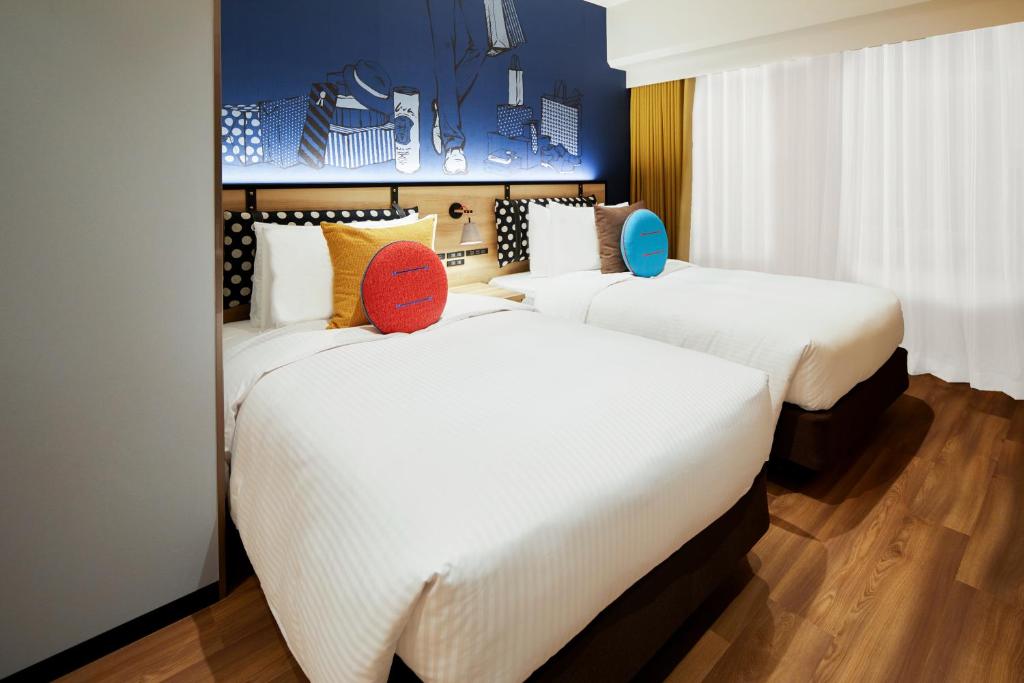 two beds in a hotel room with white sheets at Citadines Namba Osaka in Osaka
