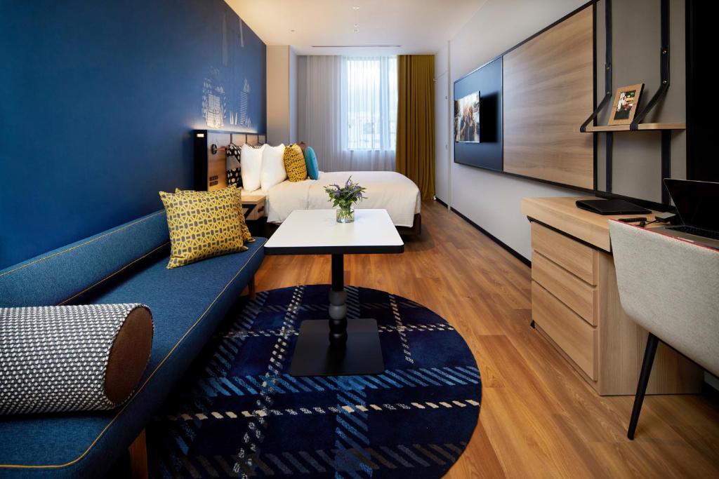 a hotel room with a couch and a bed and a tv at Citadines Namba Osaka in Osaka