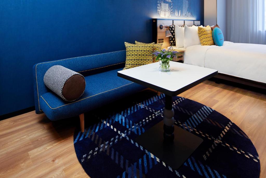 a room with a blue couch and a table and a bed at Citadines Namba Osaka in Osaka