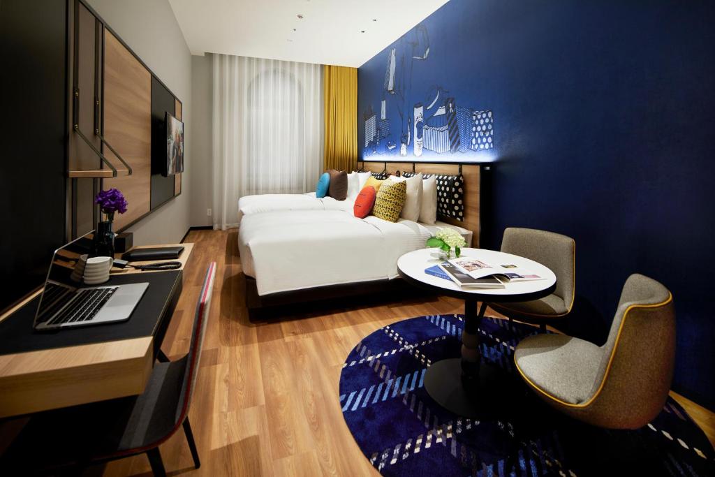 a hotel room with a bed and a desk with a table at Citadines Namba Osaka in Osaka