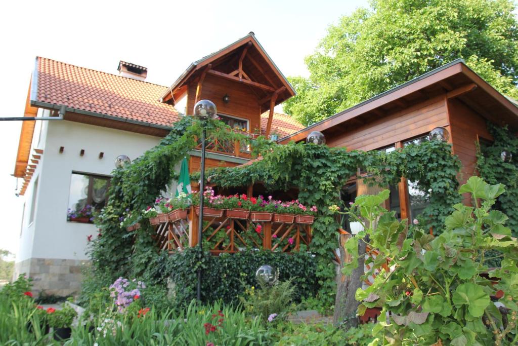 a house with a flower garden in front of it at Orehite Guest House in Samokov