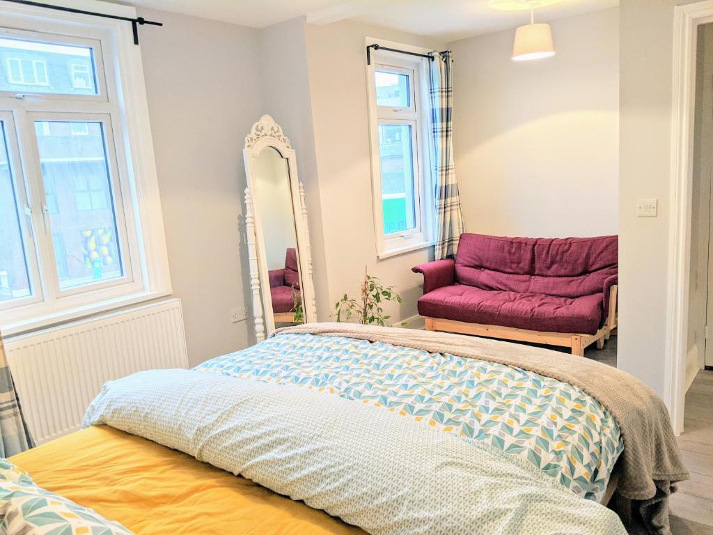 1 dormitorio con cama, espejo y silla en TopHome West Hampstead, en Londres