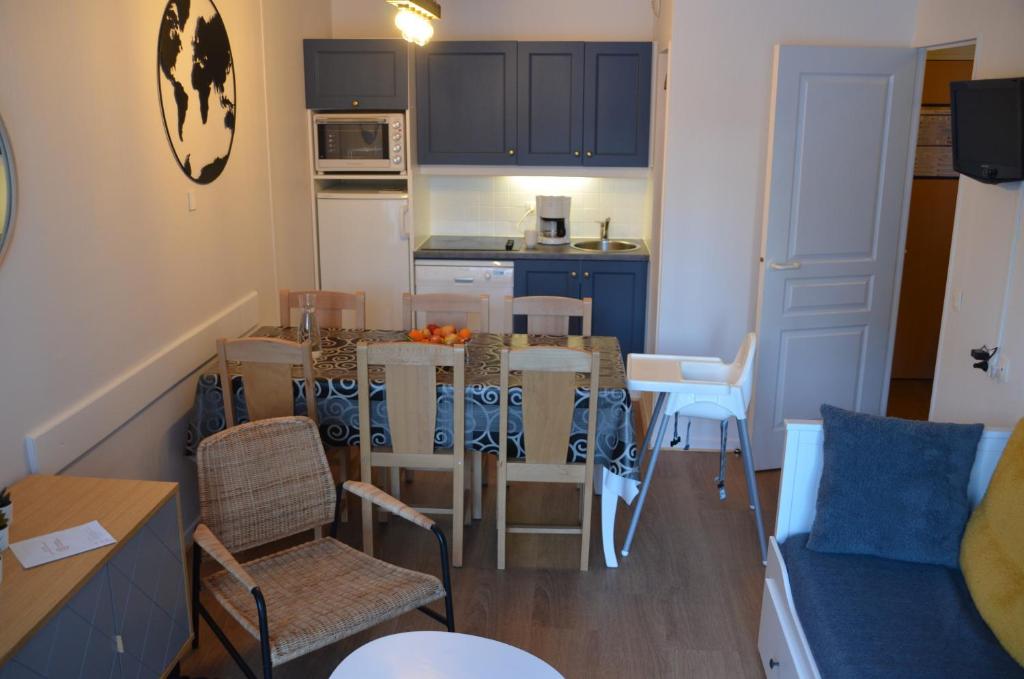 Una cocina y una sala de estar con mesa y sillas. en Pied de pistes, résidence 3 étoiles tout confort dont terrasse et piscine, en Valmeinier