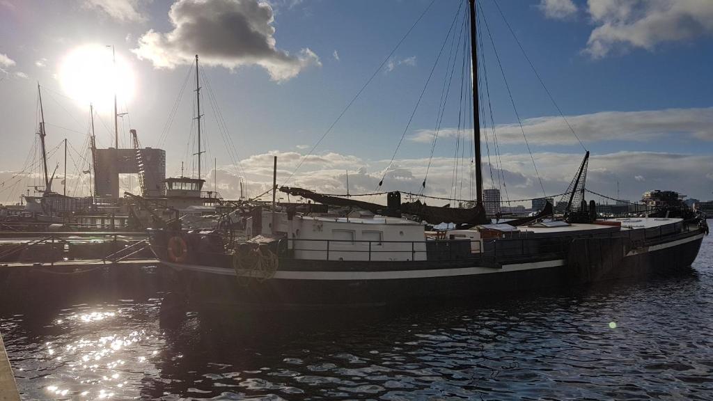 a boat is docked at a dock in the water at Hotelschip Bracksand Amsterdam City, in de zomer én de winter! in Amsterdam