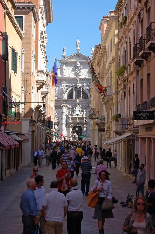 a group of people walking down a street with a building at Hotel Torino in Venice