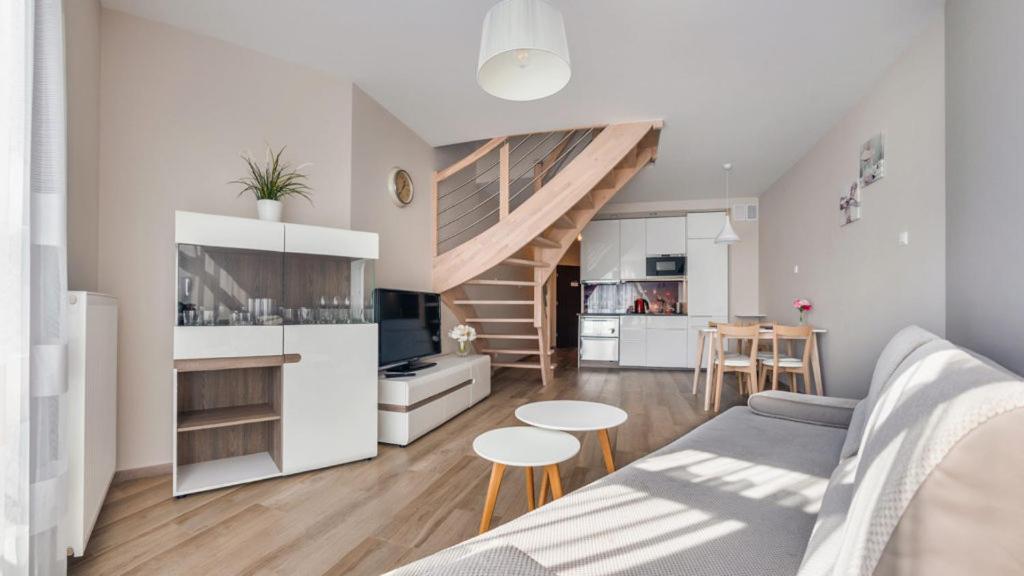Il comprend un salon avec un canapé et une cuisine avec un escalier. dans l'établissement Nowoczesny Apartament z tarasem, à Jantar