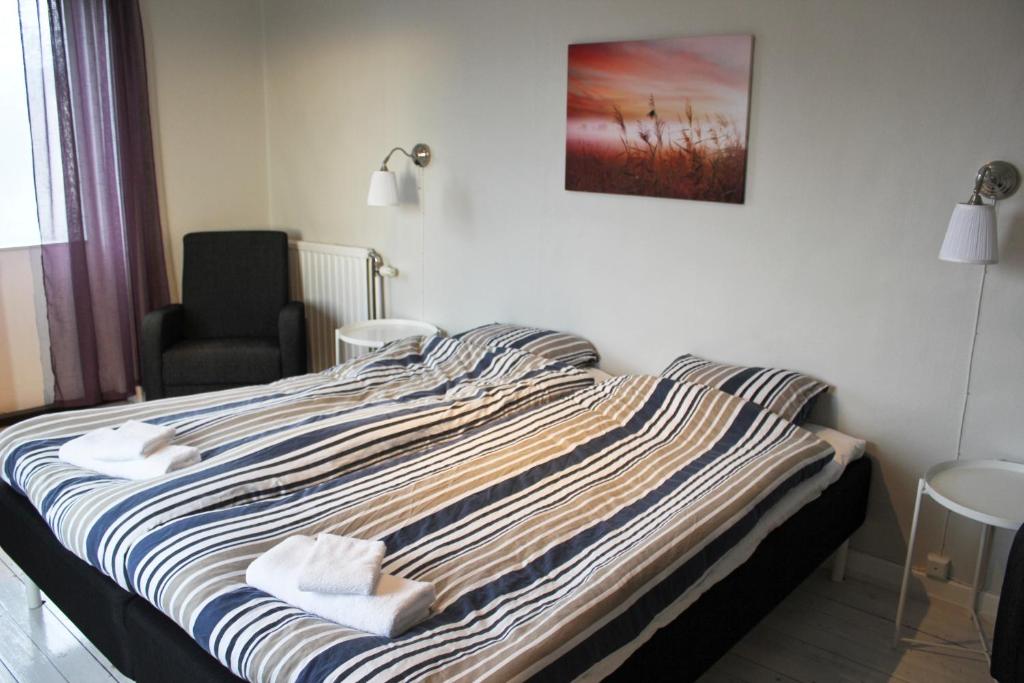 een slaapkamer met een bed met een stoel en een foto aan de muur bij Blåkråkan Bed & Breakfast in Hemse