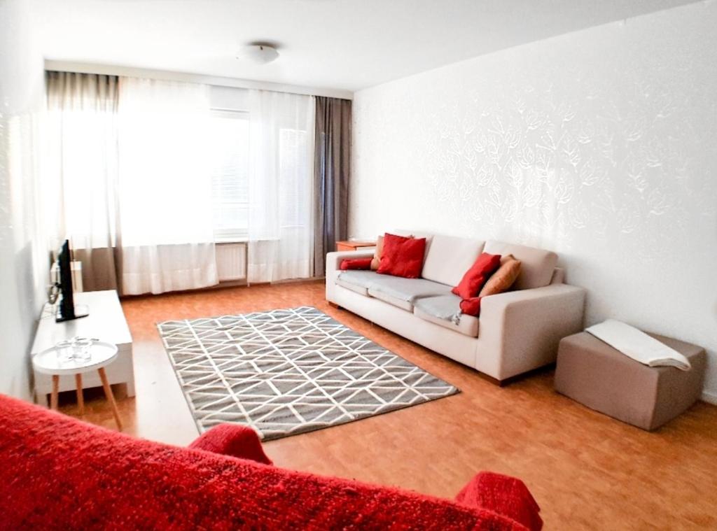 sala de estar con sofá blanco y almohadas rojas en Comfortable Apartment MILA at a good location en Kotka