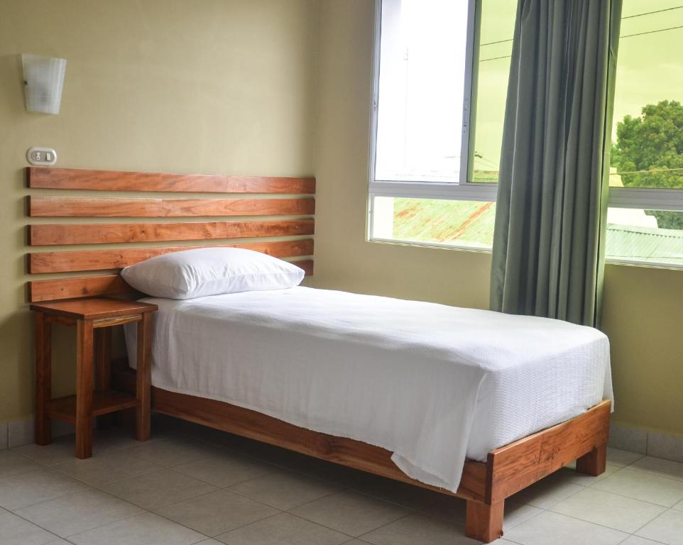 a bed with a wooden headboard in a bedroom at Pizzeria Colisseo B & B in Jinotepe