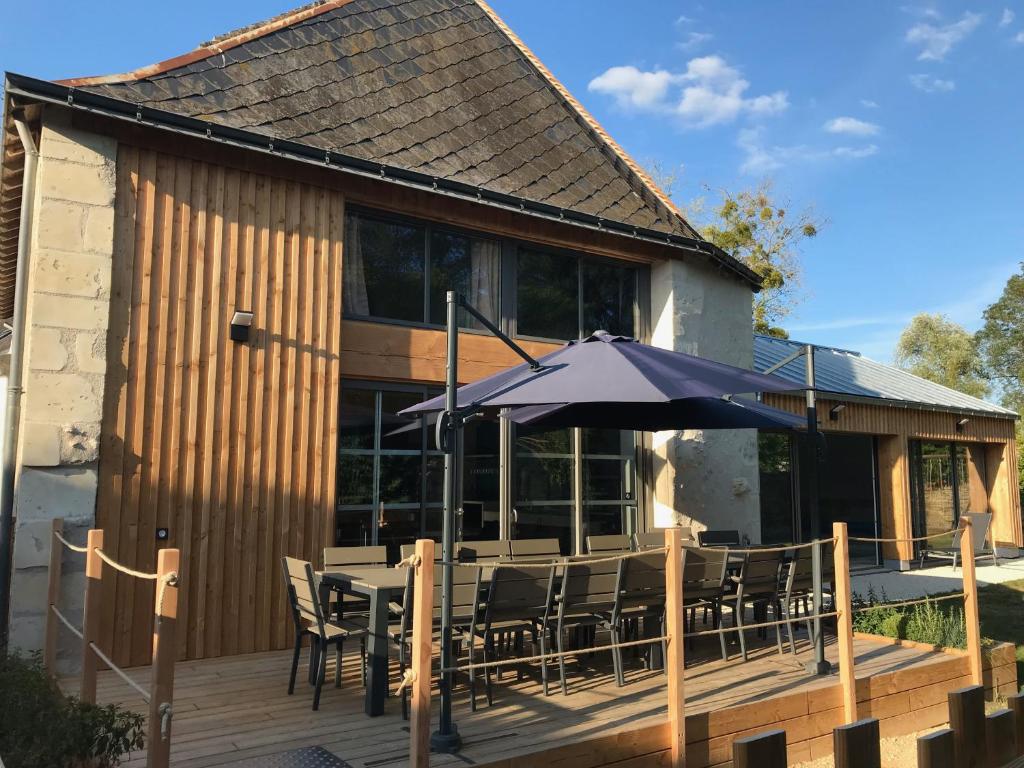 une terrasse avec une table, des chaises et un parasol dans l'établissement Gite L'Hermine, à Azay-le-Rideau