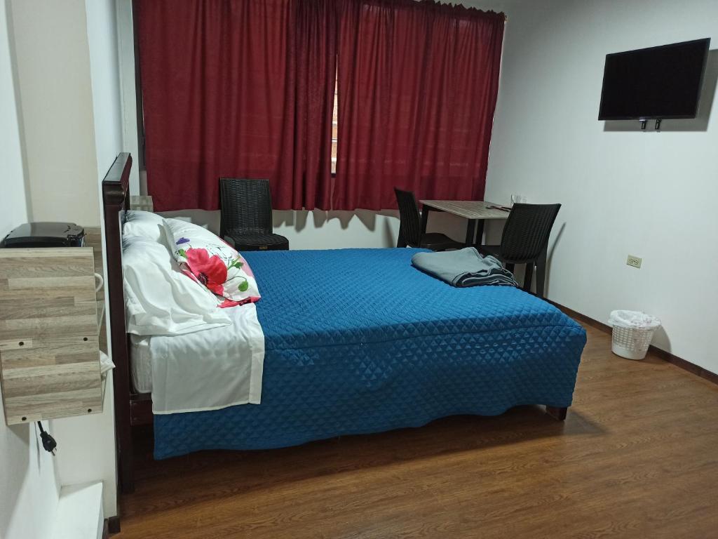 Dormitorio con cama, escritorio y TV en Habitaciones Alkimya, en Loja