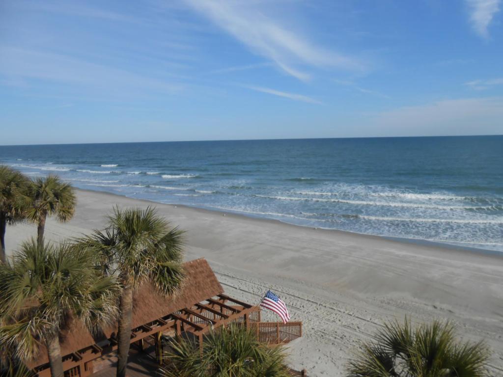 a beach with palm trees and an american flag at 0310 Waters Edge Resort condo in Myrtle Beach
