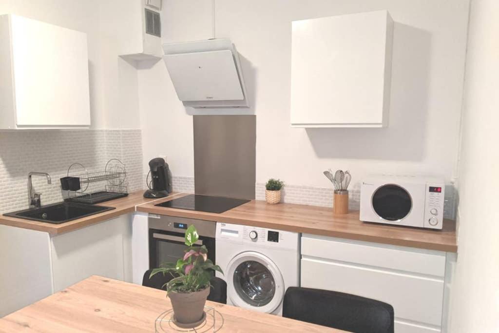 a kitchen with white cabinets and a table with a microwave at T3 Meublé et tout équipé Valence proximité de la gare in Valence