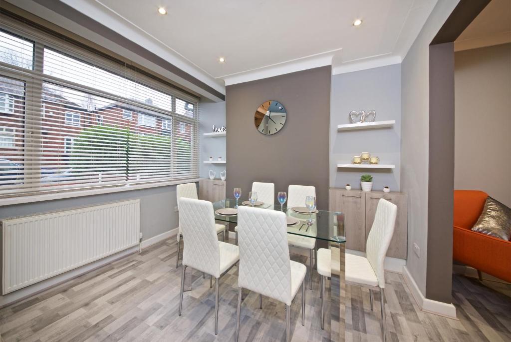 uma sala de jantar com uma mesa de vidro e cadeiras brancas em Beautiful Cozy Home With Free Parking em Manchester