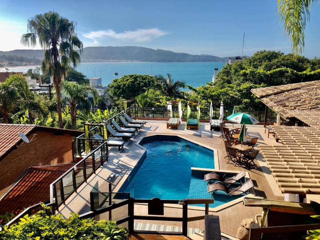 a swimming pool with a view of the ocean at Pousada Palmeiras in Bombinhas