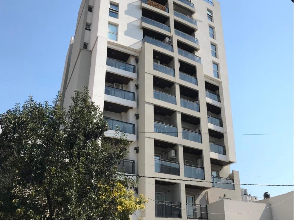 un edificio blanco alto con un árbol delante de él en Apart del Puerto 01 en Santa Fe