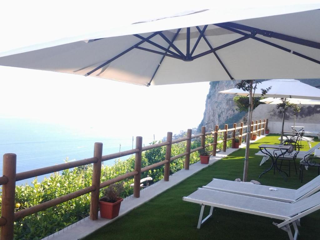 a white bench and an umbrella on a balcony with the ocean at Villa Amalfi in Amalfi