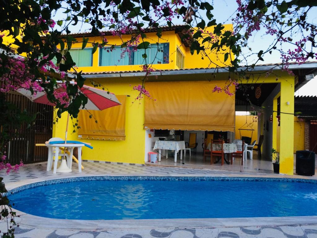 une maison jaune avec une piscine en face de celle-ci dans l'établissement Ruta Del Sol, à Mossoró