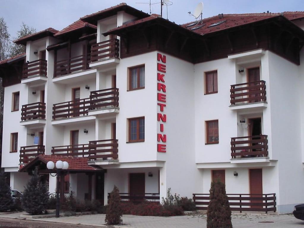 a white building with a red sign on it at Apartman Cici in Zlatibor