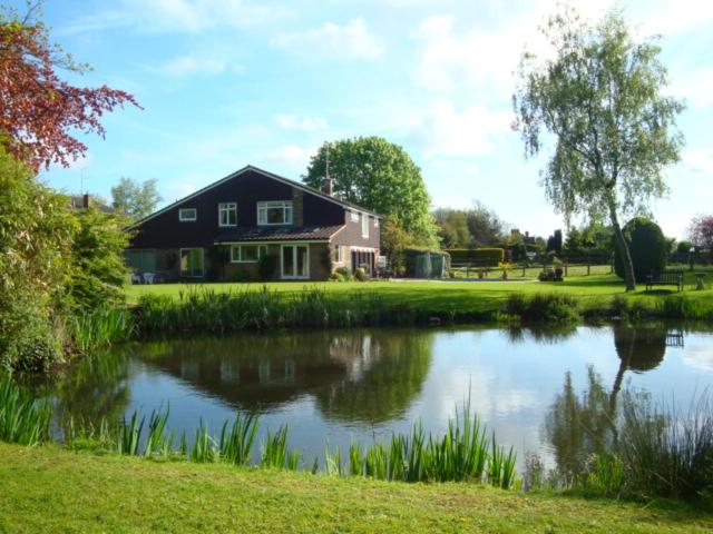 uma casa com um lago em frente a uma casa em Cobblestones em Benington