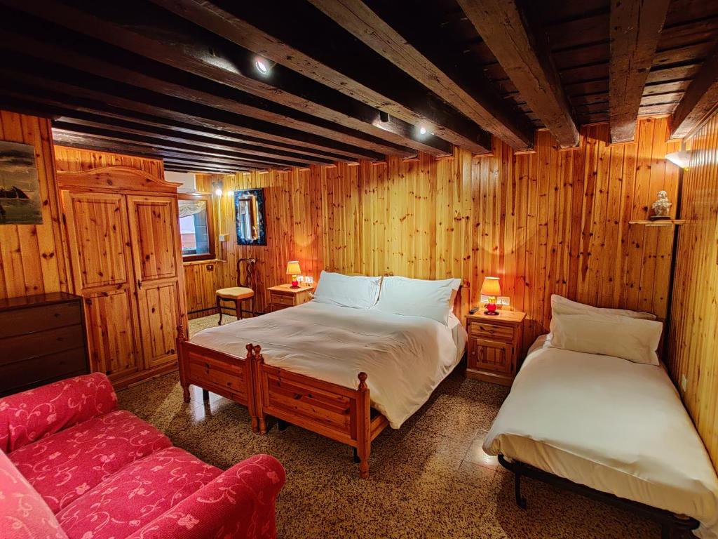 a bedroom with two beds and a red couch at La casa del pescatore: a lovely escape in Venice!! in Venice