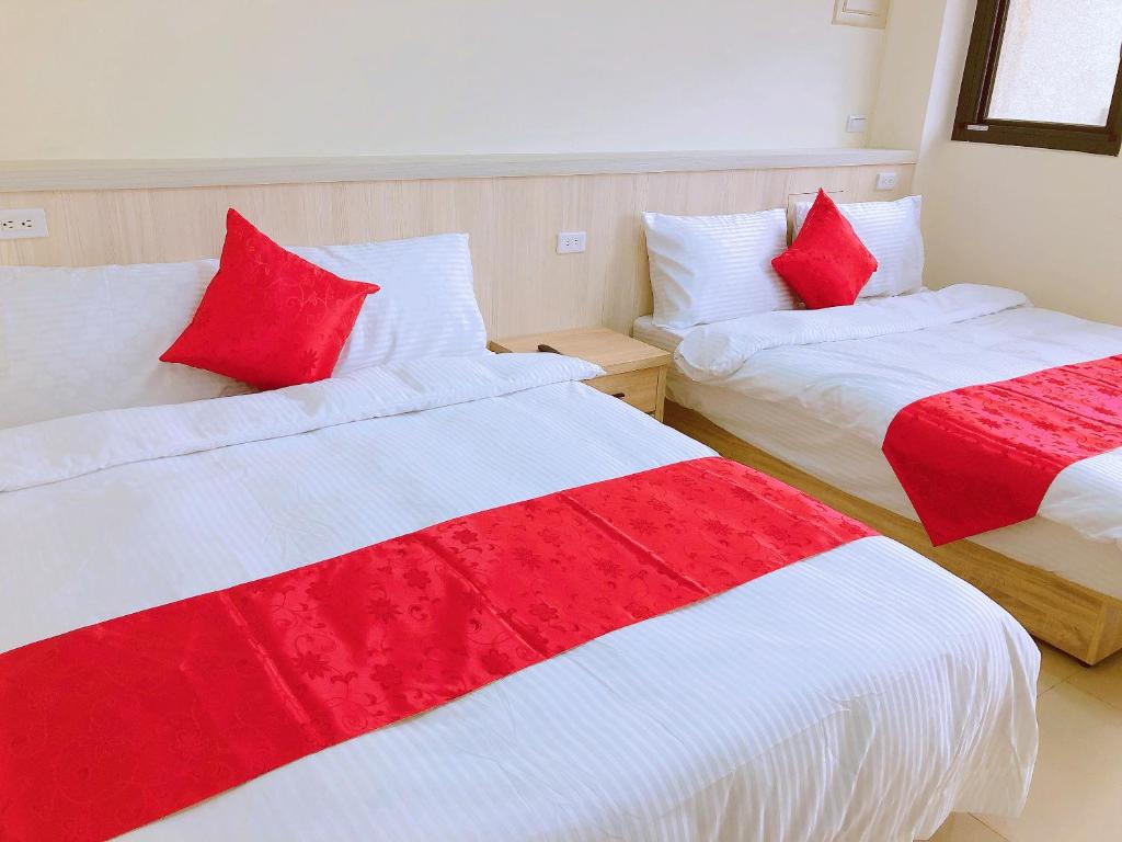 two beds in a room with red and white sheets at Yun Shan Shuei Country House in Fengping